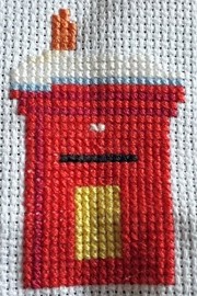 Stitching for the robin's red breast on top of the snowy post box.