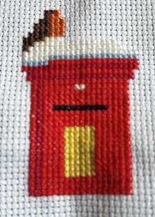 Robin red breast with brown feathers on his back sitting on top of a red post box
